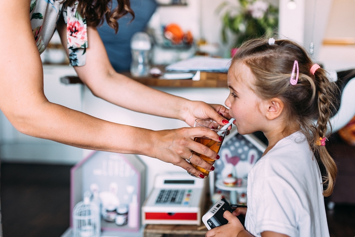 kleines Mädchen mit langen Haaren trinkt zu Hause