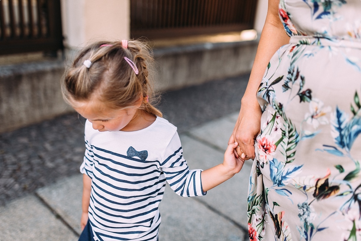 kleine Tochter an der Hand ihrer Mama